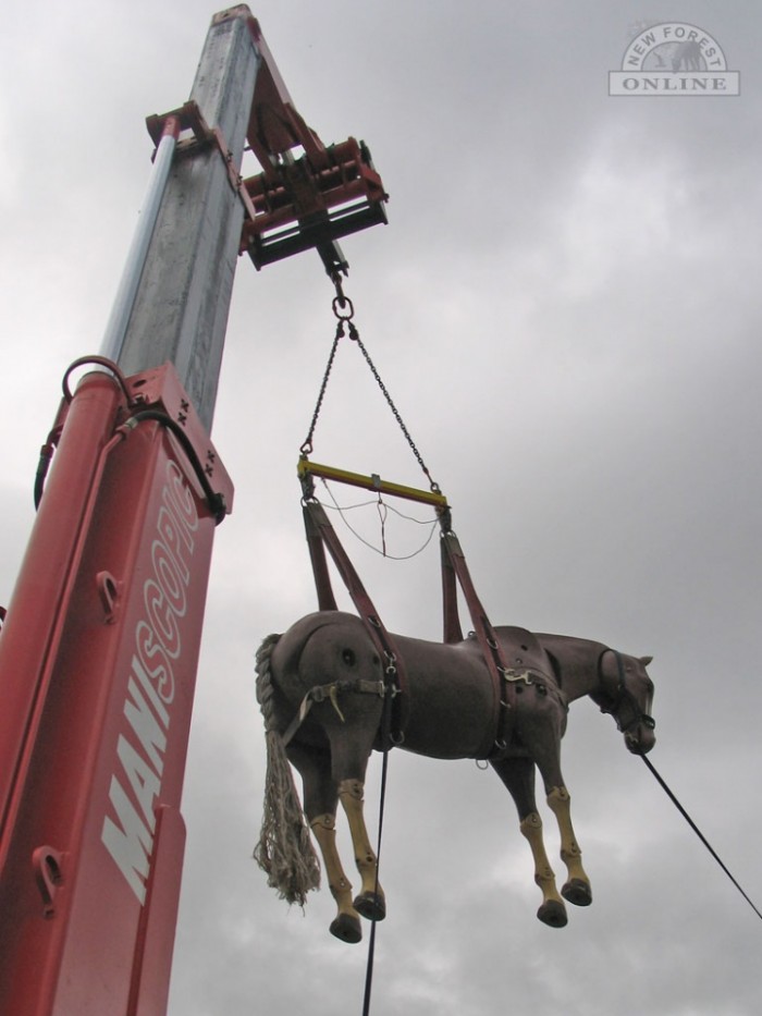 A horse. Hanging from a crane.